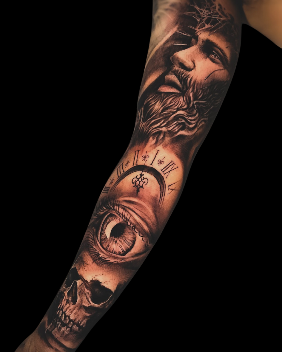 Tatuagem de antebraço fechado em realismo preto e cinza, com tema de vida, morte e fé. A arte mostra o rosto de Jesus Cristo, um olho realista fundido com um relógio, e uma caveira na base. Tattoo masculina com forte simbolismo.