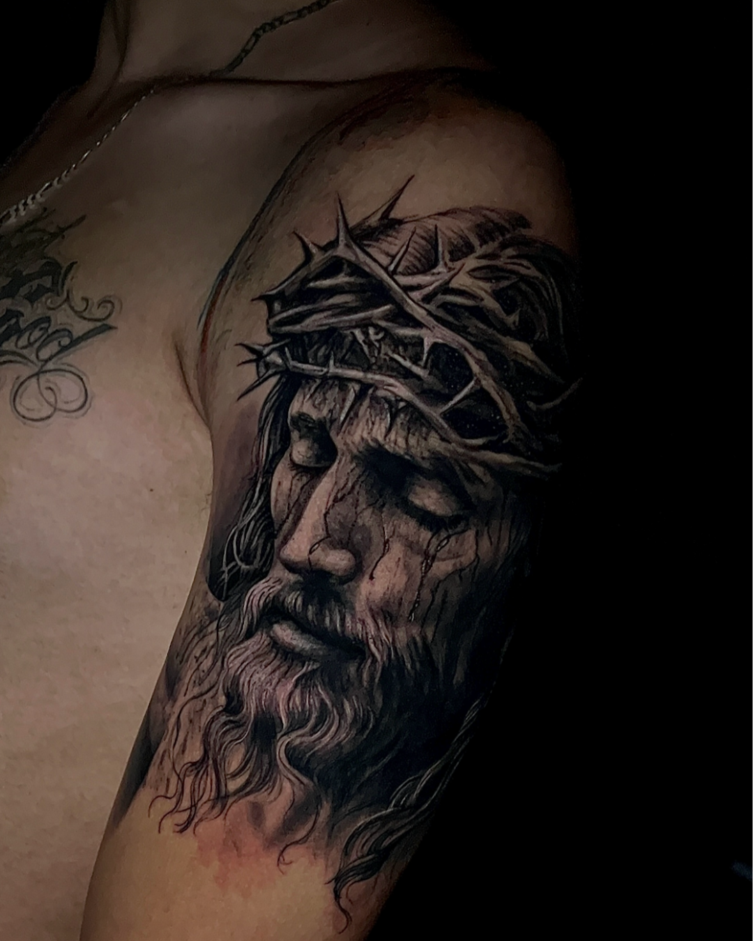 Tatuagem religiosa de Jesus Cristo com coroa de espinhos em realismo P/B.