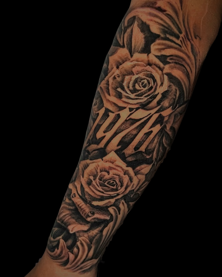 Antebraço fechado em realismo P/B com rosas detalhadas e a data 1976.