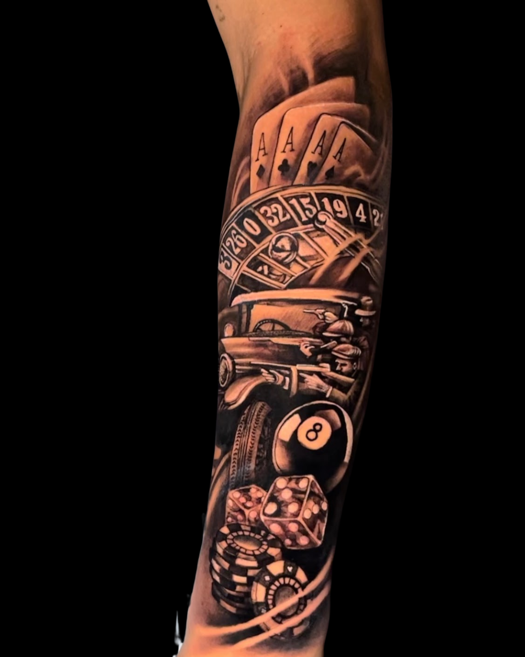 Tatuagem de antebraço fechado com tema de cassino e máfia em realismo preto e cinza. A arte inclui cartas de poker, roleta, dados, fichas, bola 8 e um carro antigo com gângsteres, compondo uma tattoo sobre sorte e jogos.