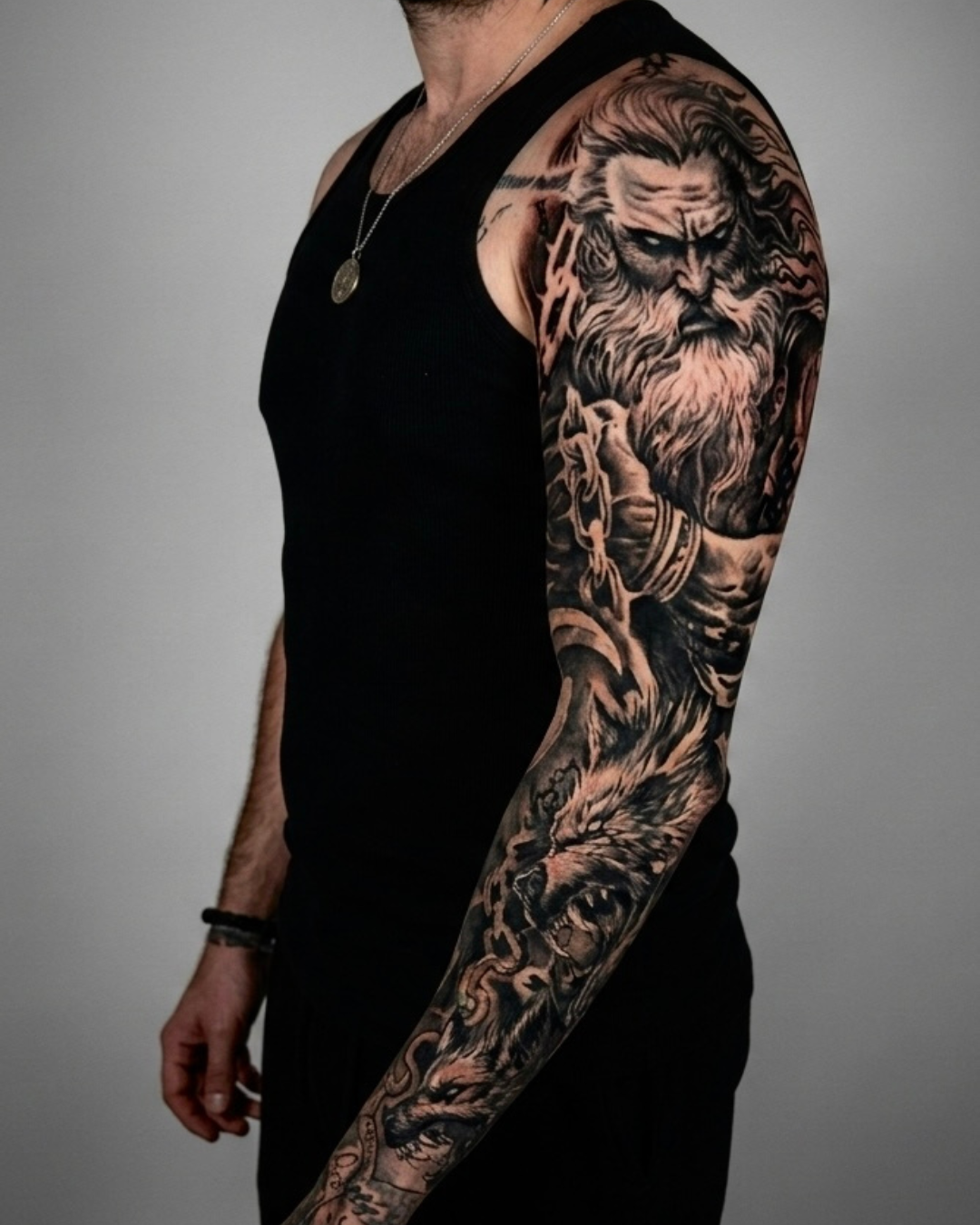 Tatuagem realista em preto e cinza no braço com figura mitológica e composição personalizada. Fechamento de braço.